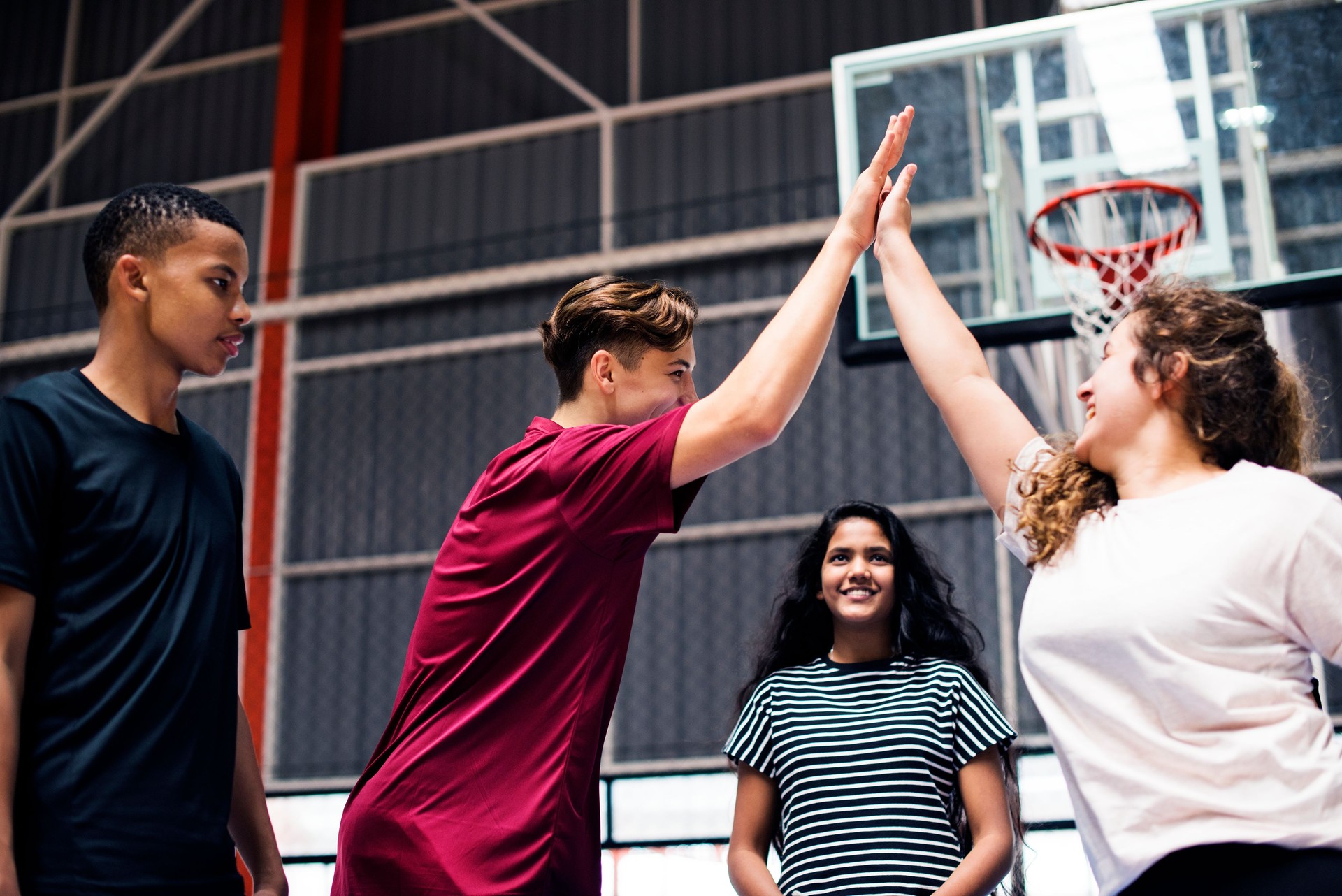 Group of teenager friends on a basketball court giving each other a high five
